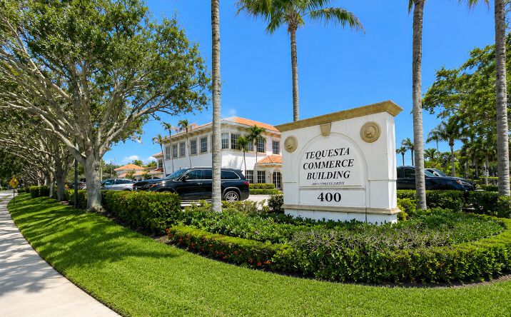 Monument sign for Tequesta Commerce Building at 400 North Cypress Drive with the two-story office building and landscaped grounds visible behind it.